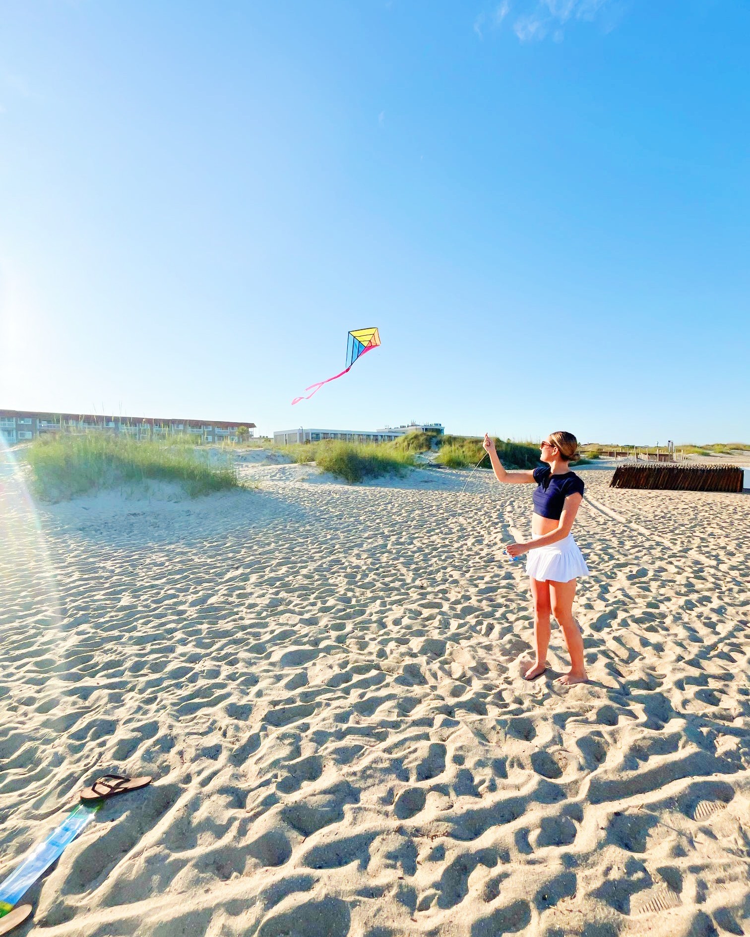 A woman on the beach flying a kite.