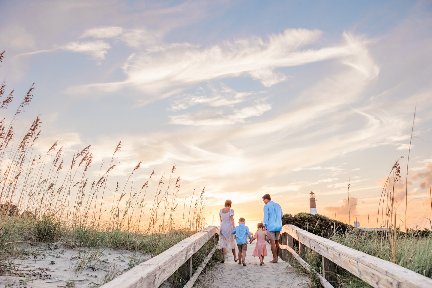 A family of four walking the dock towards the beach.