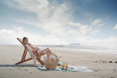Mother on Tybee Island beach holding her sleeping daughter