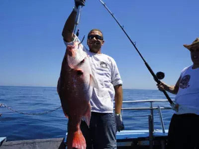 A fisherman holding a large fish on a line.