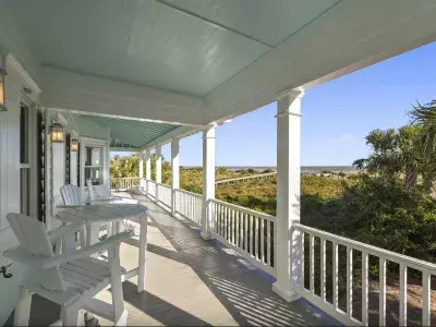 Covered balcony with seating and view of the dock to the beach