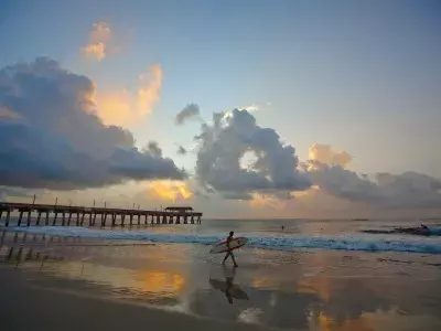Surfer walking into the ocean at sunset