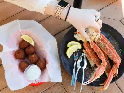 A hand reaching for crab legs arranged on a plate