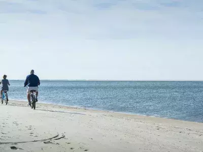 A family of two bike riding on the beach